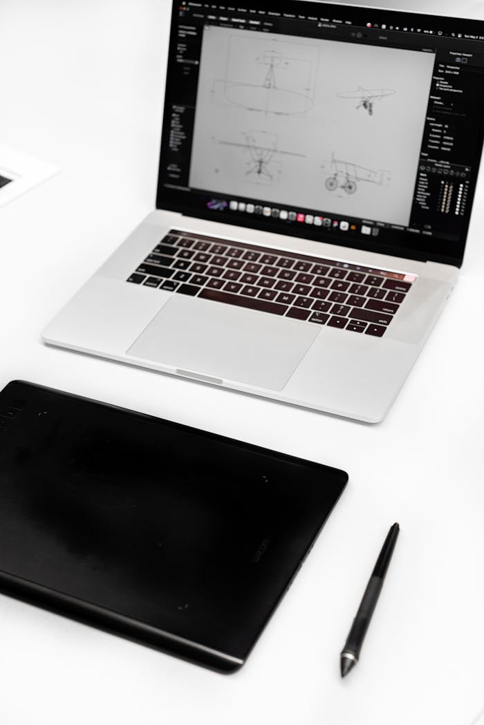 Top view of a designer's workspace featuring a laptop and digital tablet.